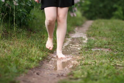 Low section of woman walking walking in puddle