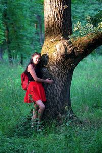 Full length of woman on tree trunk in forest