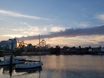 Sailboats moored at harbor against sky during sunset