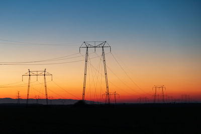 Silhouette electricity pylon against sky during sunset