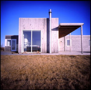 House on field against clear blue sky