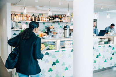 Businesswoman with laptop walking towards checkout counter in cafe