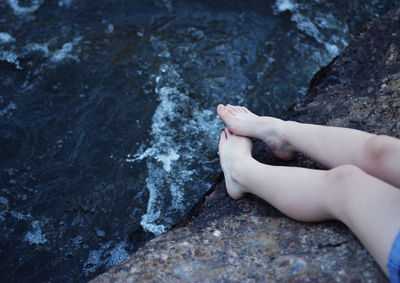 Low section of woman on rock above water