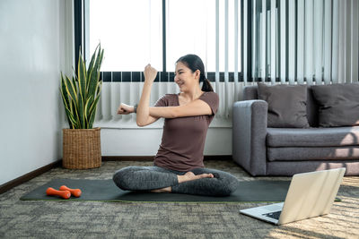 Young woman exercising on sofa at home