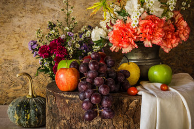 Still life with fruits were placed together with a vase of flowers beautifully.