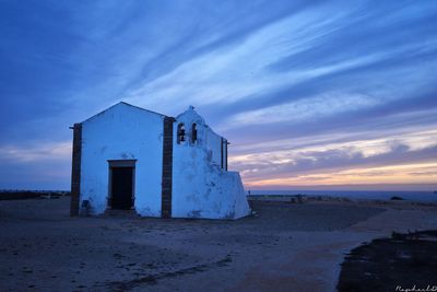 Built structure on beach against sky during sunset
