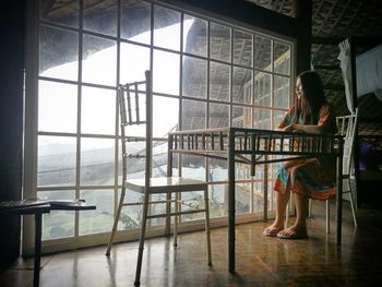 Woman sitting on chair by window at restaurant