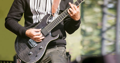 Midsection of man playing guitar at concert