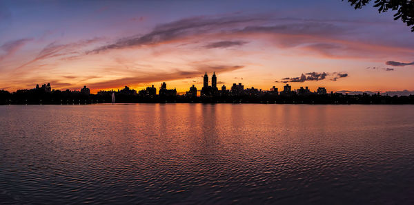 Silhouette buildings by city against sky during sunset