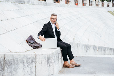 Businessman using mobile phone while sitting outdoors