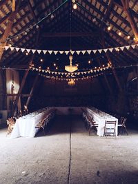 Low angle view of illuminated chandelier hanging over dining tables at wedding reception