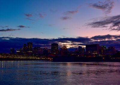 Illuminated city buildings against sky at sunset