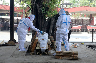 Rear view of people working on street in city