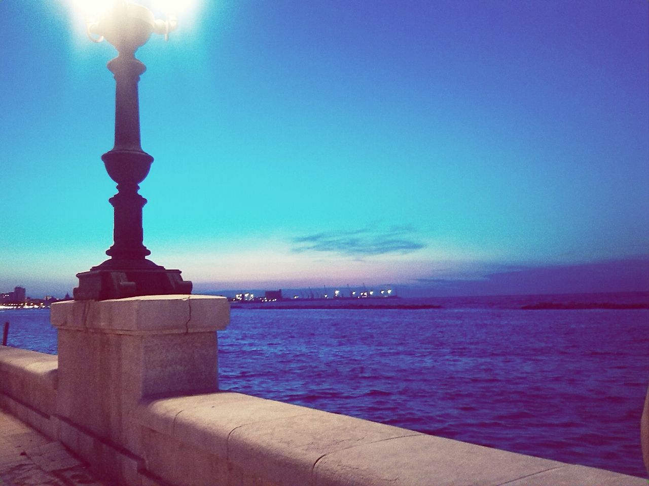 sea, water, sky, built structure, horizon over water, blue, architecture, lighthouse, illuminated, scenics, guidance, tranquil scene, tranquility, dusk, building exterior, nature, tower, beauty in nature, auto post production filter, waterfront