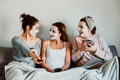 Women with facial mask sitting on sofa at home