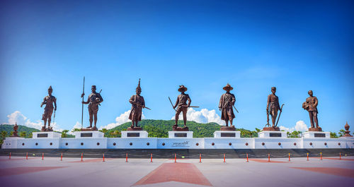 Statues in row against clear blue sky