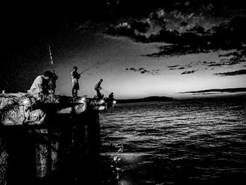 People sitting by sea against sky