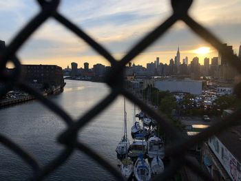 View of buildings in city seen through chainlink fence