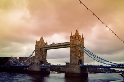 Bridge over river against cloudy sky