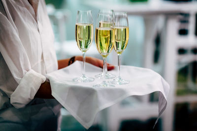 Midsection of waiter carrying champagne at restaurant