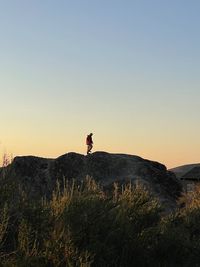 Man standing on rock against sky during sunrise 