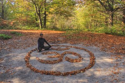 Woman meditating while sitting by symbol on land