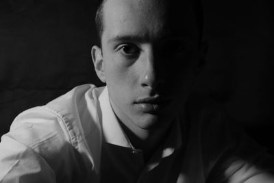 Portrait of young man against black background