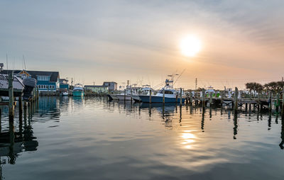 Boats moored in harbor at sunset