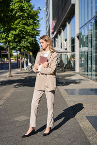 Portrait of young woman standing on street in city