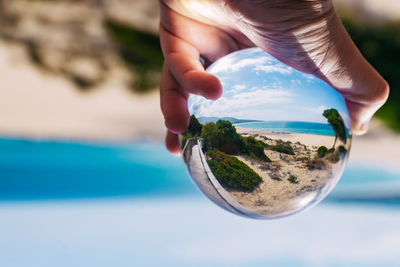 Midsection of person holding glass against sky