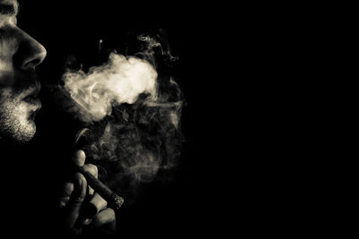 Man smoking cigarette against black background