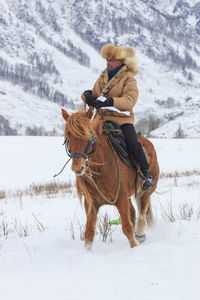 Man riding horse on snow field against sky