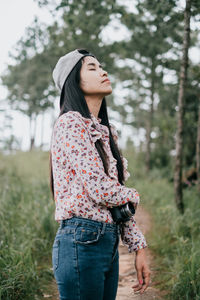 Young woman looking away while standing on field