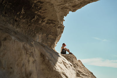 Low angle view of man on rock against sky