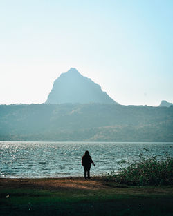 Rear view of silhouette man looking at sea against sky