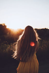 Rear view of woman standing against sky during sunset