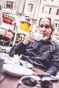 Portrait of man drinking coffee in city