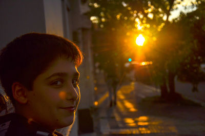 Close-up portrait of smiling boy standing on pathway during sunset