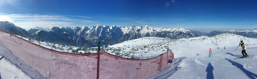 Panoramic view of people skiing on snow covered land