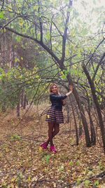 Portrait of woman standing by tree in forest