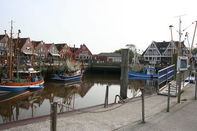 Boats moored at harbor by buildings against sky