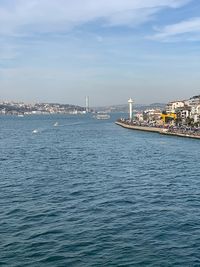 Sea by buildings in city against sky