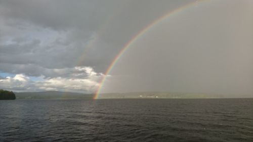 Scenic view of rainbow over sea against sky
