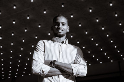 Portrait of young man standing against illuminated light