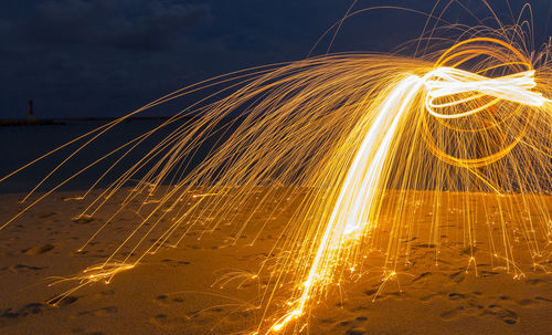 Light trails in sea against sky at night