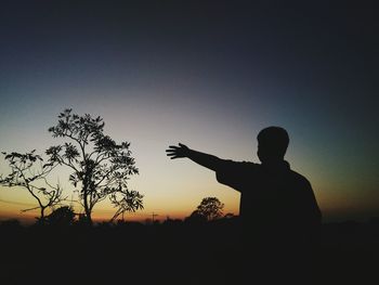 Silhouette man standing by tree against sky during sunset