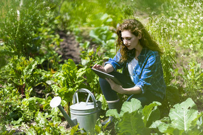 Young woman looking away while sitting on plants