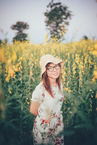 Portrait of smiling woman standing by flowering plants on land