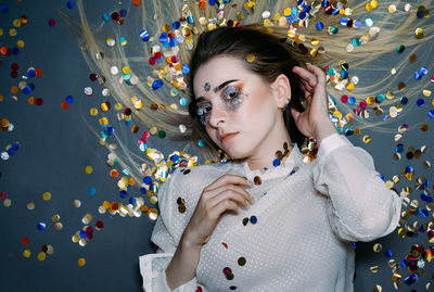 Portrait of woman with confetti against wall 