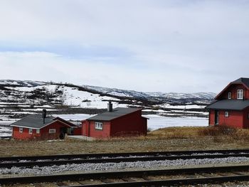 Houses by snowcapped mountain against sky